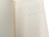 an open book with a handwritten page in it on a white surface