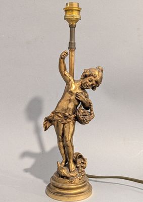 une lampe sur laquelle est représentée la statue d'un garçon tenant un panier