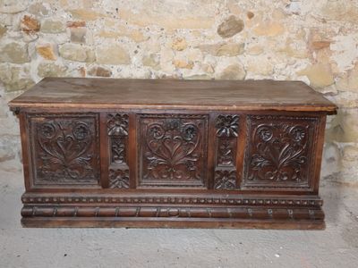 a wooden chest with carvings on it in front of a stone wall