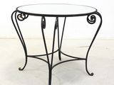 an iron table with a glass top on a white floor