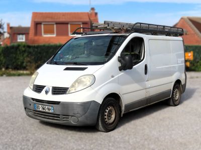 une camionnette blanche garée sur un parking, avec une maison en arrière-plan