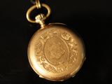 a gold pocket watch that is on a black table