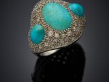 a close up of a turquoise stone and diamond ring on a black surface