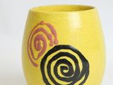 a yellow vase with a black and pink rose on it