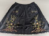 a black skirt with embroidered flowers and fringes on a white background