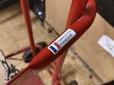 a red bike with a sticker on the handlebars