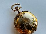 a gold pocket watch on a white surface