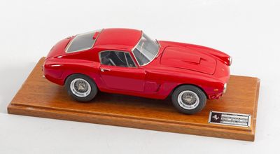 une maquette de voiture rouge posée sur un socle en bois