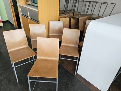 six wooden chairs sitting in a room next to a book shelf
