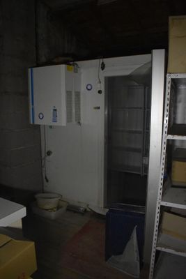une photo d'une pièce dans laquelle se trouvent un réfrigérateur et des étagères