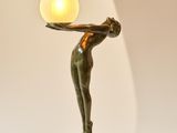 a statue of a woman holding a lamp on a table