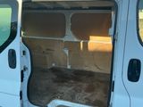 une camionnette blanche dont la porte est ouverte, garée sur le bord de la route