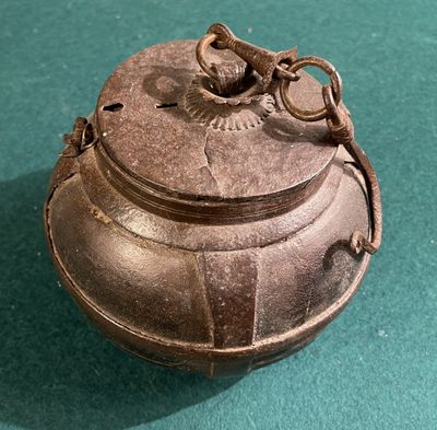 a metal container with a handle on a green surface