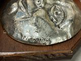 a silver plate with a face on it sitting on a shelf