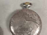 a silver pocket watch sitting on a table next to another pocket watch