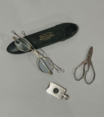une paire de ciseaux, une paire de lunettes et une autre paire de lunettes posées sur une table