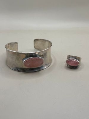silver cuff bracelet with a pink stone set on a white surface