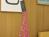 a table with a lamp that has a pink ribbon on it