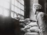 black and white photo of a man sitting in a chair with a gun