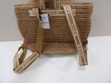 beige and white straw bag with strap and tag on it