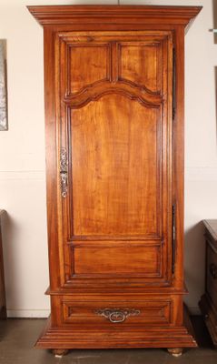 une grande armoire en bois dans une pièce où un miroir est accroché au mur