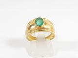 a close up of a gold ring with a green stone