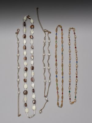 Plusieurs colliers et bracelets différents sont exposés sur un fond blanc