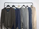 four sweaters hanging on a clothes rack in a room