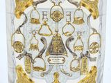 an image of a white and gold scarf with a picture of a clock and other items