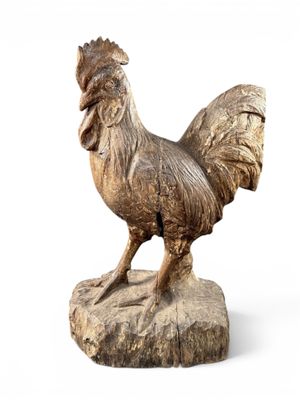 statue en bois représentant un coq posé sur un rocher, sur fond blanc