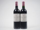 two bottles of red wine sitting next to each other on a white surface