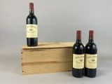 trois bouteilles de vin sont posées devant une caisse en bois