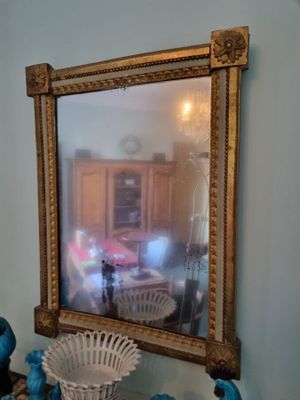 a mirror on the wall above a table with blue vases