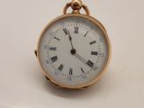 une petite montre de poche en or avec des chiffres romains