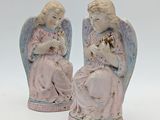 deux figurines d'anges assis l'un à côté de l'autre sur une surface blanche