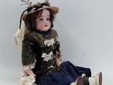 doll sitting on the ground wearing a hat and dress