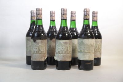 six bouteilles de vin sont alignées sur une surface blanche