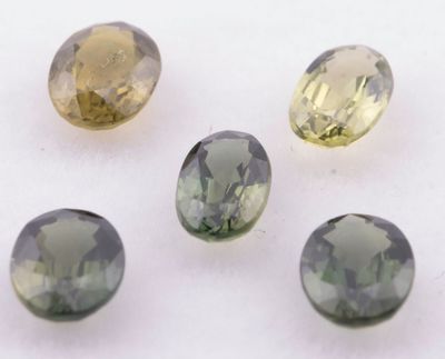 quatre pierres précieuses de couleurs différentes sont disposées en ligne sur une surface blanche