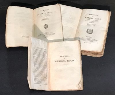 trois livres ouverts posés sur une table l'un à côté de l'autre