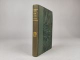 un vieux livre à la couverture verte posé sur une surface blanche