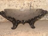 a metal bowl sitting on a stand in front of a stone wall