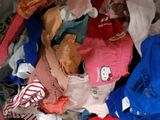 a white bag full of clothes and clothes on a bed