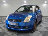 the blue suzuki swift is parked in a room with checkered floor
