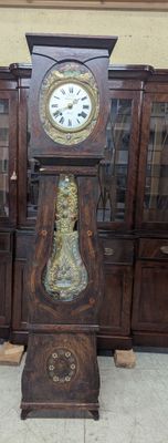 a grandfather clock sitting on the floor in front of a bookcase