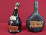 two bottles of liquor sitting next to each other on a red surface