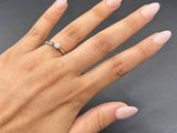 the woman ' s hand is holding a ring with a diamond on it
