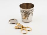 a silver cup with a pair of scissors next to it