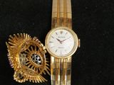 a gold bracelet and a gold watch on a black pillow