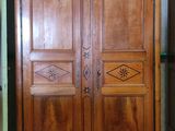 a wooden armoire in a room with a green wall