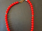 un collier de perles rouges rehaussé de touches dorées sur un fond en cuir noir